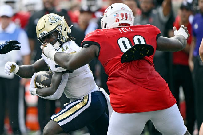 Sep 21, 2024; Louisville, Kentucky, USA; Georgia Tech Yellow Jackets running back Jamal Haynes (11) runs the ball despite the facemark from Louisville Cardinals defensive lineman Dezmond Tell (99) during the first quarter at L&N Federal Credit Union Stadium. Mandatory Credit: Jamie Rhodes-Imagn Images