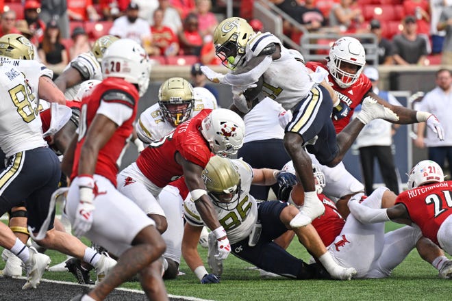 Sep 21, 2024; Louisville, Kentucky, USA; Georgia Tech Yellow Jackets running back Jamal Haynes (11) leaps over the top to score a touchdown against the Louisville Cardinals during the first half at L&N Federal Credit Union Stadium. Mandatory Credit: Jamie Rhodes-Imagn Images