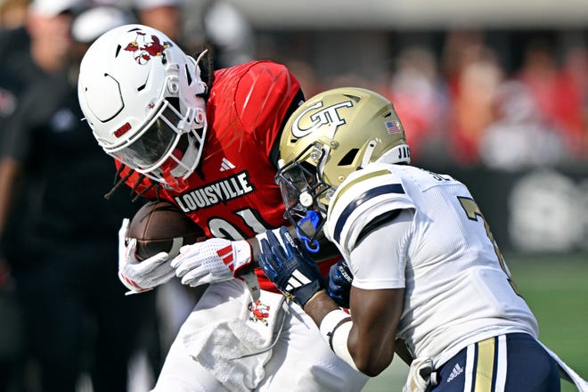 Sep 21, 2024; Louisville, Kentucky, USA; Louisville Cardinals running back Donald Chaney (21) tries to break free from the tackle of Georgia Tech Yellow Jackets defensive back Taye Seymore (7) during the first half at L&N Federal Credit Union Stadium. Mandatory Credit: Jamie Rhodes-Imagn Images