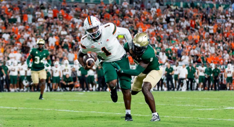 Miami Hurricanes quarterback Cam Ward (1) runs with the ball as South Florida Bulls defensive back Tavin Ward (2) tries to stop him in the second half of their NCAA college football game at the Raymond James Stadium on Saturday, Sept. 21, 2024, in Tampa, Fla.