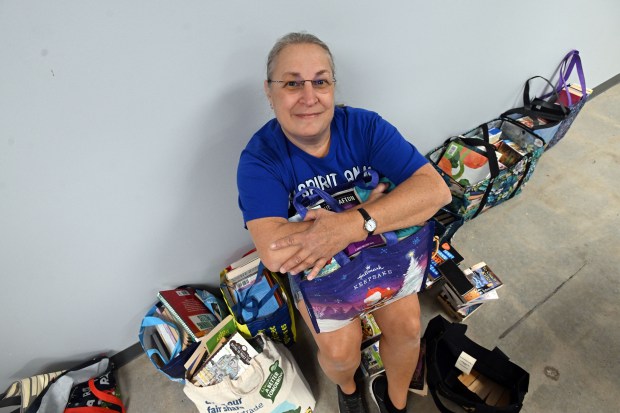 Rhonda Kleinspehn of Sinking Spring, the second person in line at the start, relaxes with some of her finds during the 2024 Book Bonanza on Friday at the Berks County South Campus in Mohnton. (BILL UHRICH - READING EAGLE)