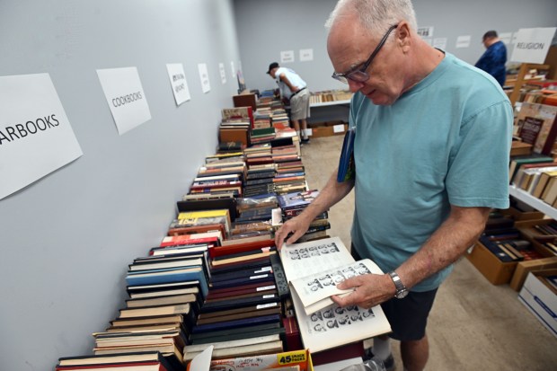 Stacy Shannon of Ontelaunee Township looks for his father in a 1939 Reading high School yearbook during the 2024 Book Bonanza on Friday at the Berks County South Campus in Mohnton. (BILL UHRICH - READING EAGLE)