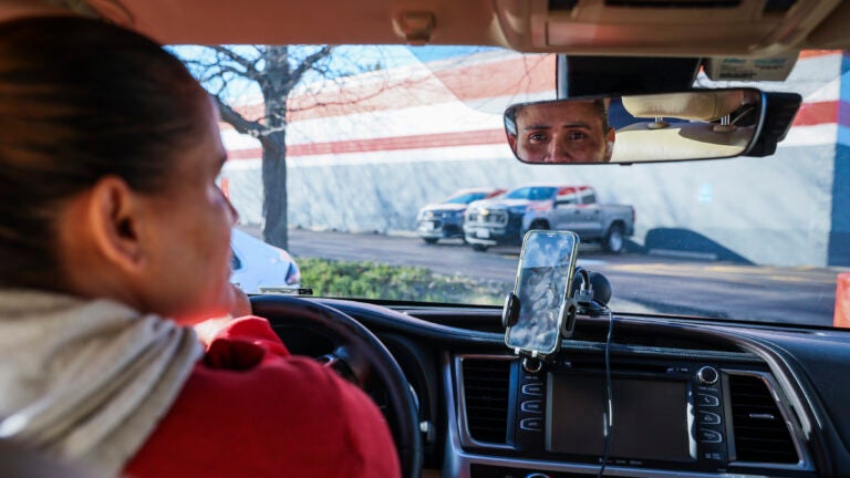 Victoria (last name withheld) poses for a portrait in her car, which she uses to drive for rideshares throughout the state.