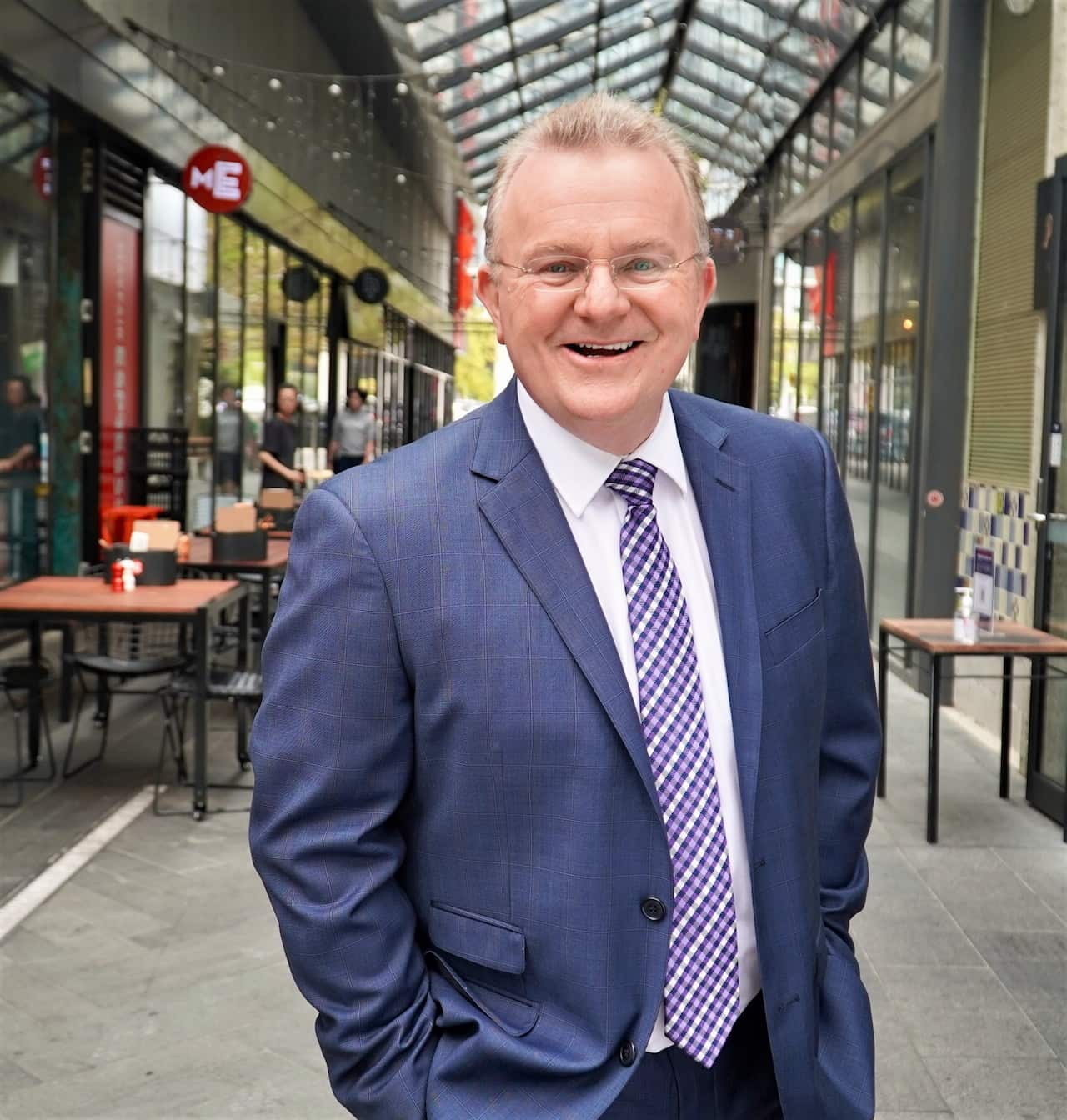 A man in a blue suit and tie is smiling.