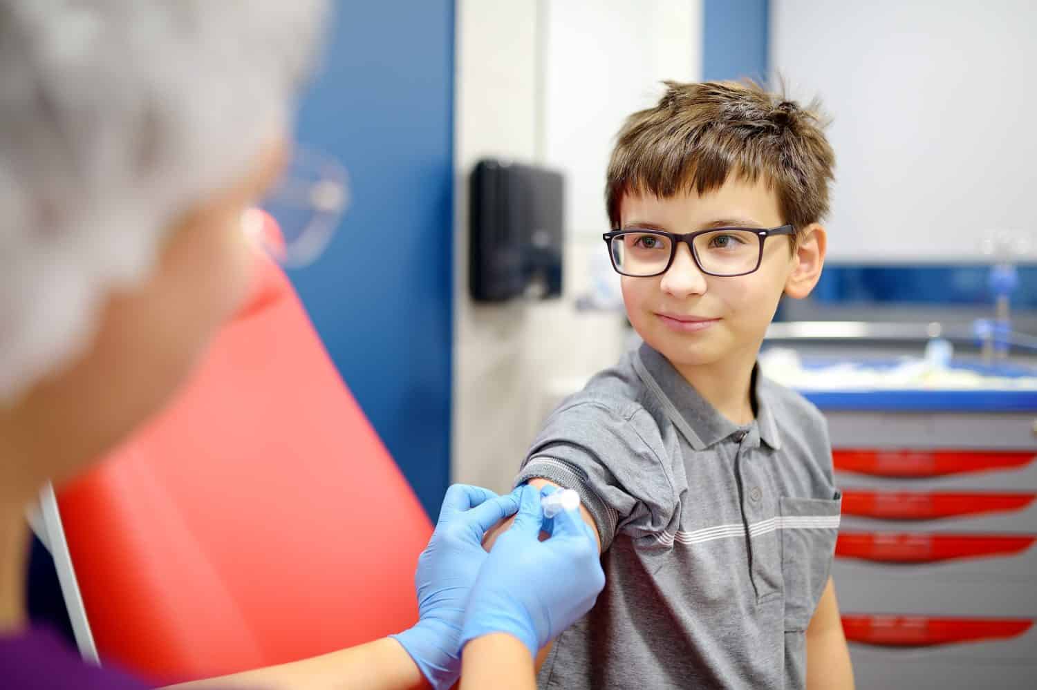 A boy is being vaccinated. A child is given a vaccine during an epidemic or outbreak of a disease. A kid during routine vaccination