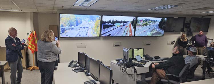 Elected officials and Washington State Department of Transportation employees and invited guests take a look at the monitor as the part-time shoulder lane was activated Thursday on State Route 14. Photo by Paul Valencia