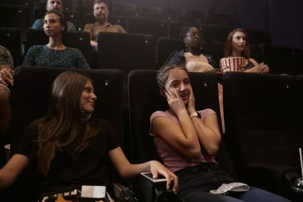 Reopening Cinema. Two girls watching a scary movie.