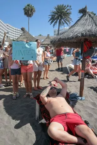 A protester holds a sign reading 'The Canary Islands have a limit' as thousands march on Las Americas beach during a demonstration to protest against mass tourism, in Arona on the Spanish Canary island of Tenerife, on October 20, 2024.