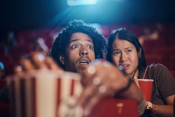 Couple watching a crime movie in cinema.