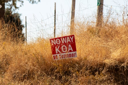 A sign saying ‘No Way KOA, No Terramor’ in brush near a barbed-wire fence.