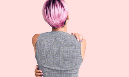 A woman hugging herself, pictured from behind