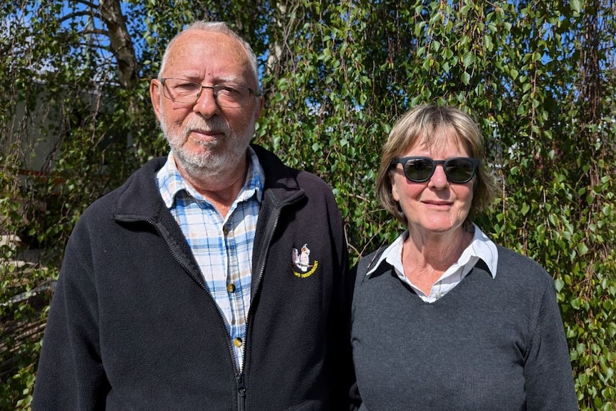 A man and woman with their arms around each other smile at the camera.