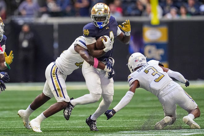 Oct 19, 2024; Atlanta, Georgia, USA; Notre Dame Fighting Irish running back Jeremiyah Love (4) runs against Georgia Tech Yellow Jackets linebacker Tah'j Butler (15) and defensive back Ahmari Harvey (3) during the first half at Mercedes-Benz Stadium. Mandatory Credit: Dale Zanine-Imagn Images