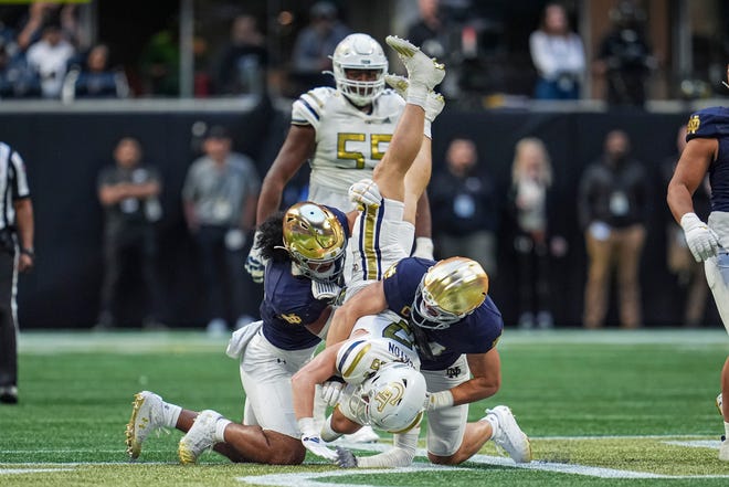 Oct 19, 2024; Atlanta, Georgia, USA; Georgia Tech Yellow Jackets wide receiver Bailey Stockton (87) is upended by Notre Dame Fighting Irish linebacker Kyngstonn Viliamu-Asa (27) and linebacker Jack Kiser (24) during the second half at Mercedes-Benz Stadium. Mandatory Credit: Dale Zanine-Imagn Images