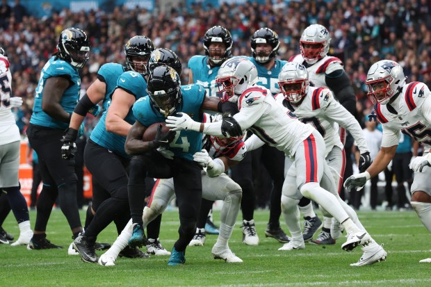 Jacksonville Jaguars running back Tank Bigsby (4) is tackled during the first half of an NFL football game against the New England Patriots, Sunday, Oct. 20, 2024, in London. (AP Photo/Ian Walton)