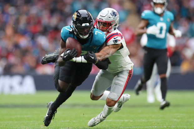 Jacksonville Jaguars wide receiver Brian Thomas Jr. (7) is tackled by New England Patriots cornerback Christian Gonzalez (0) during the first half of an NFL football game, Sunday, Oct. 20, 2024, in London. (AP Photo/Ian Walton)