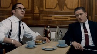 Tom Hardy as Ronnie Kray and Tom Hardy as Reggie Kray sitting at a diner in Legend