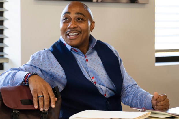 A man in a blue dress shirt smiles as he speaks