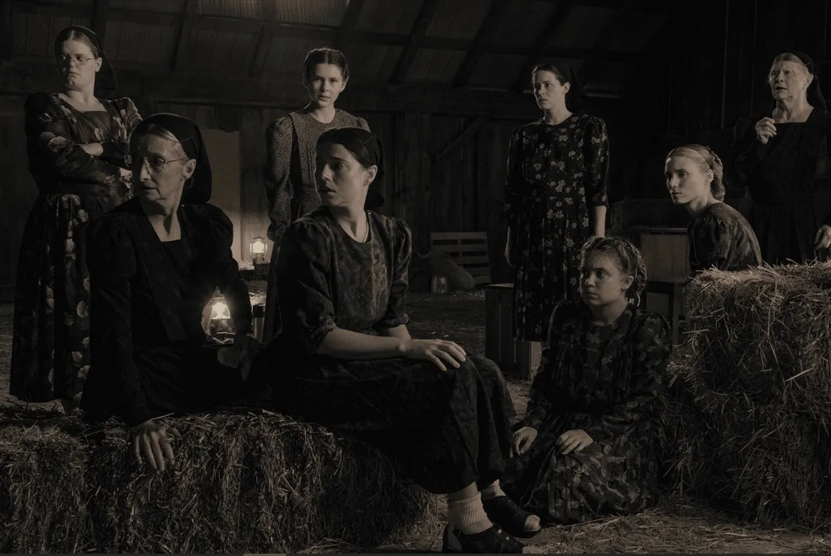 A group of Mennonite woman discuss in a barn in 