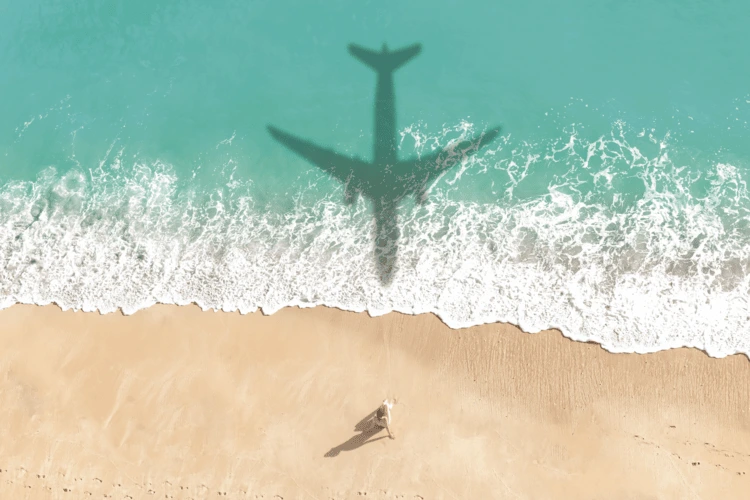 Airplane shadow reflecting on beach water.