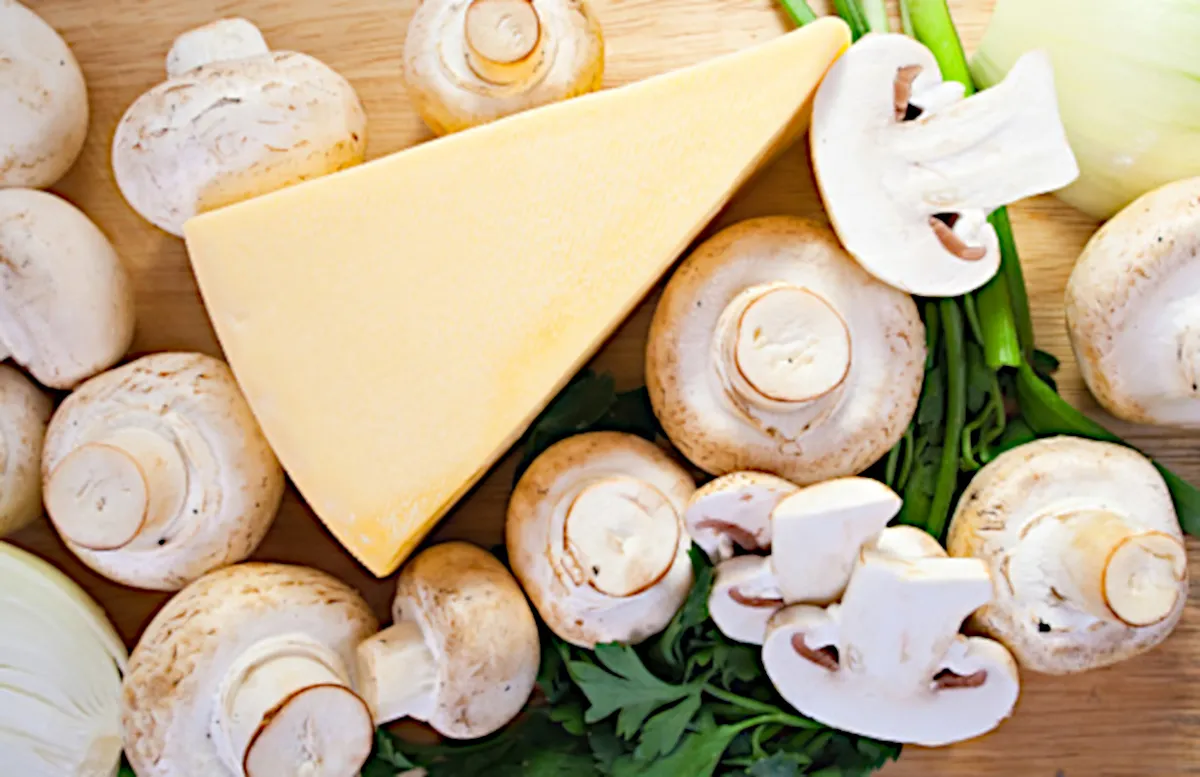 Closeup of champignon mushroom with cheese on cutting board.