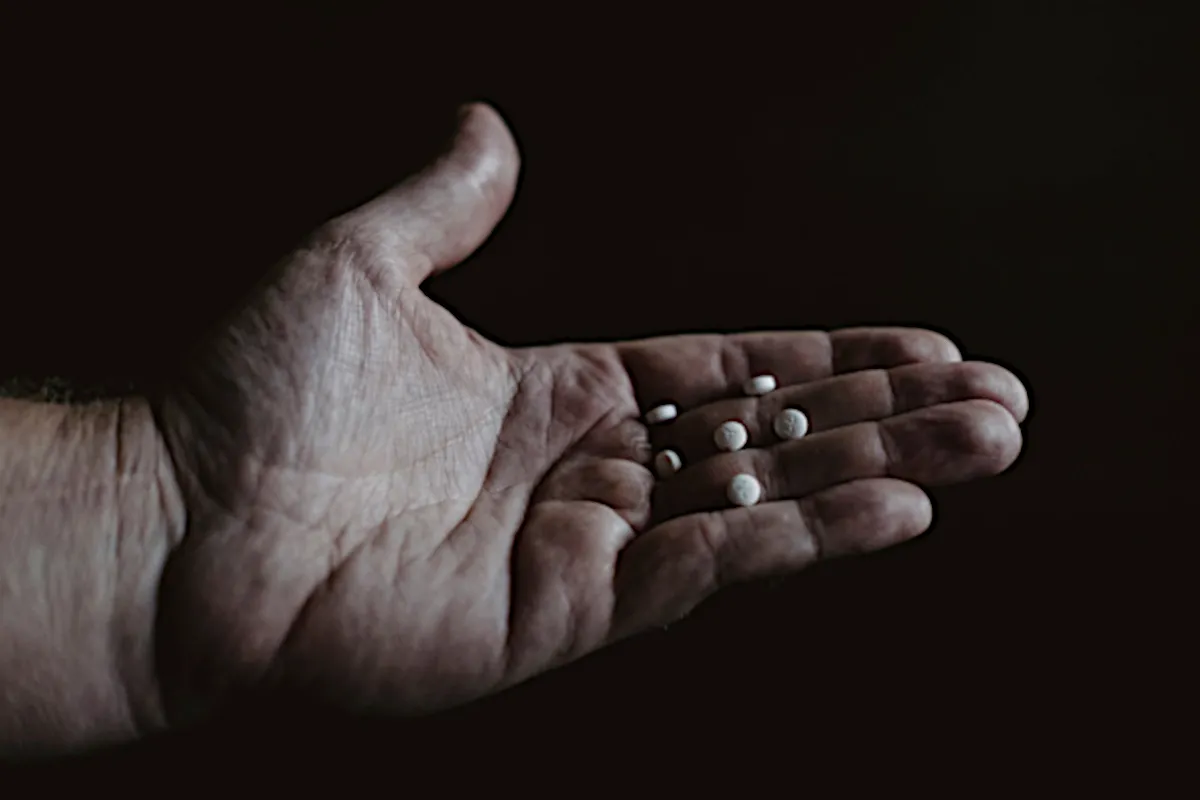 Closeup photo of a flat-palmed hand holding six white pills.