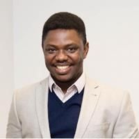 Headshot of Godwin Aleku. Godwin is wearing a shirt and cream jacket. 