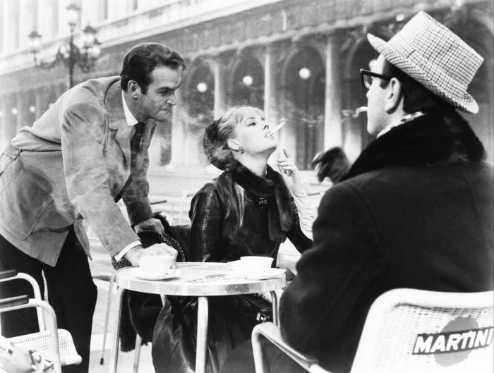 Stanley Baker, Jeanne Moreau and Alex Revidis at a café table on a Venetian square in a scene from ‘Eva’