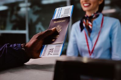 African american man holding boarding pass and passport at airline check-in desk at international airport