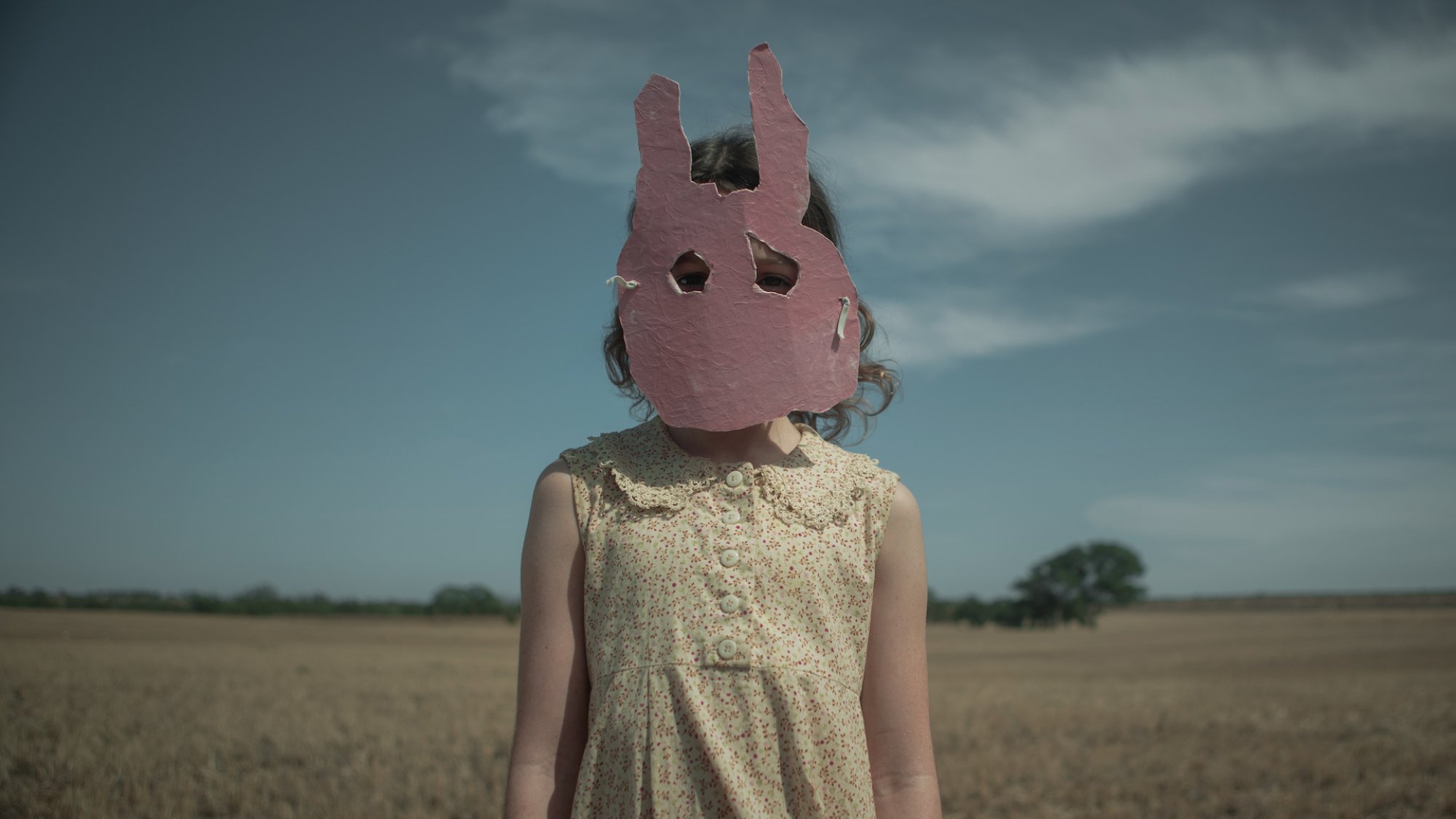 A child wears a pink cardboard rabbit mask in the film 