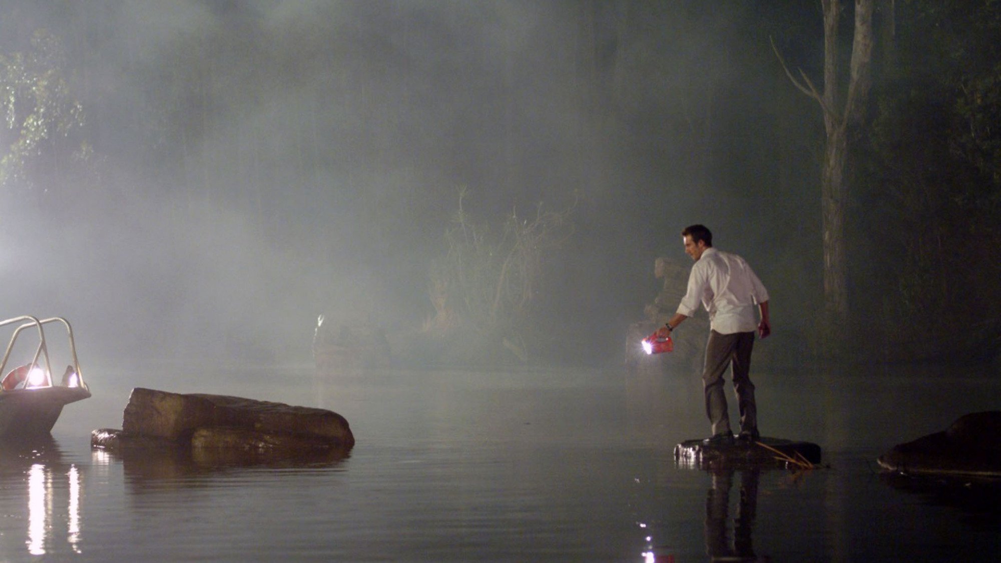 Michael Vartan stands by a river at night holding a torch in the film 