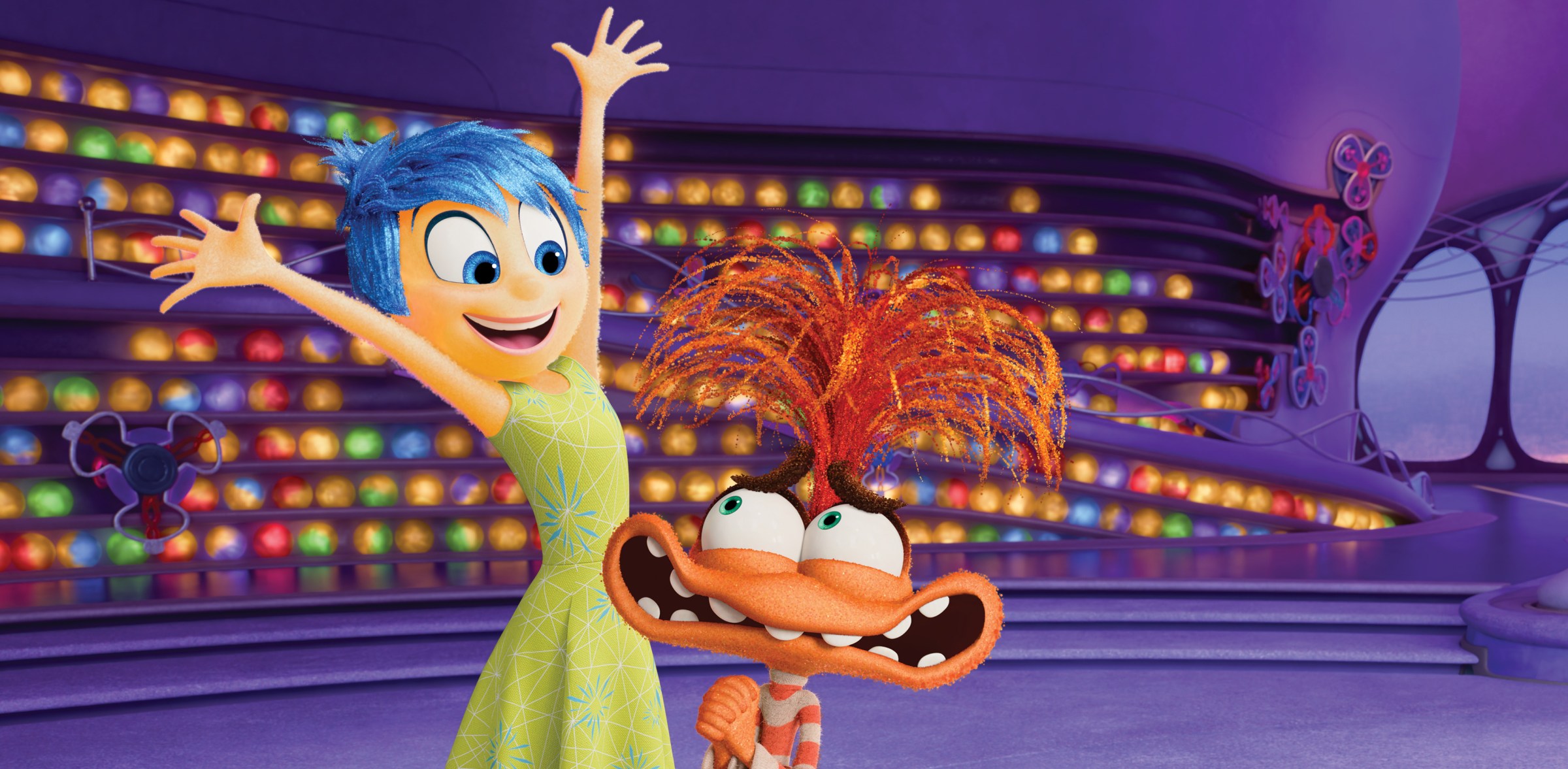 Joy, a yellow figure, throws her hands up as she greets Anxiety, an orange muppet-like figure, in Inside Out 2