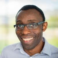 Headshot of Lekan Daramola. Lekan is wearing a striped shirt and is smiling at the camera.