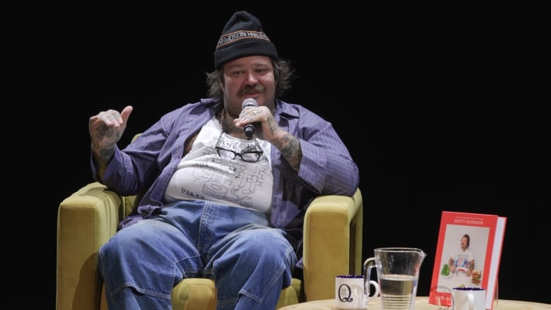 Matty Matheson sits in an armchair against an all-black background.