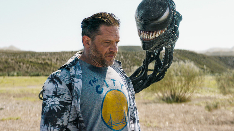 Tom Hardy as a dishevelled Eddie Brock with a leering Venom head looking down at him in Venom: The Last Dance