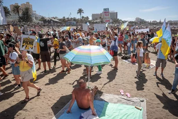 Protesters march on Las Americas beach during a demonstration to protest against mass tourism