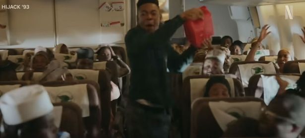 A man holds a gasoline can in an aeroplane aisle