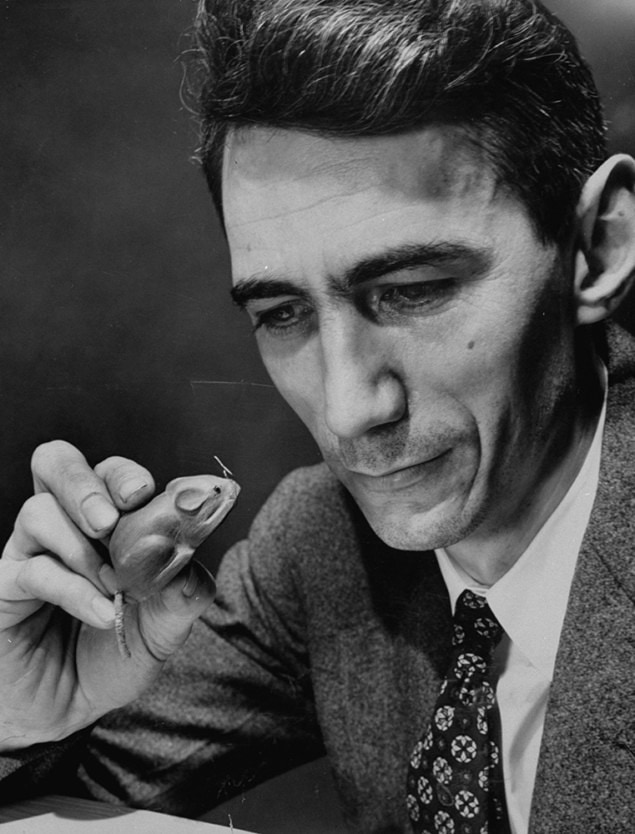 Claude Shannon holding a wooden mouse