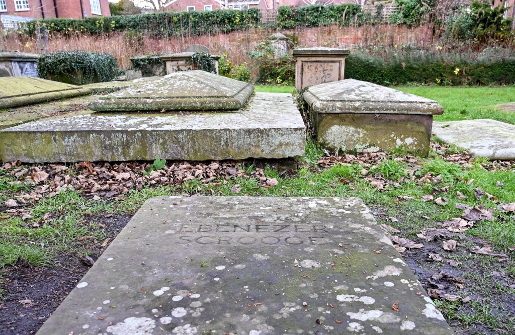 Broken gravestone of the fictional character Ebenezer Scrooge at St Chad's Church, Shrewsbury, with officers investigating the vandalism