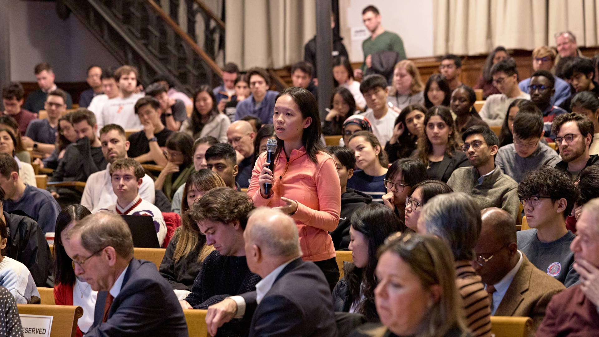 A student asks a question into a microphone 