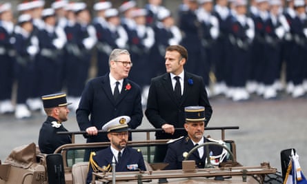 Macron and Starmer stand as they are driving in a military vehicle