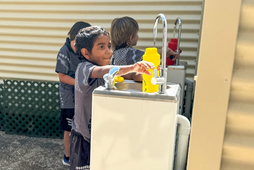 child filling up a water bottle