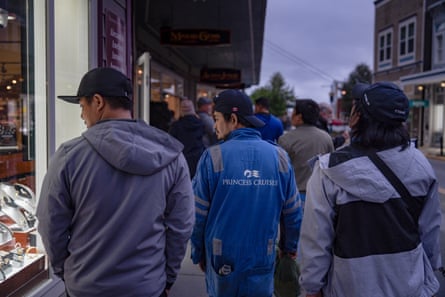 Three people look in a shop window as they walk past in Juneau