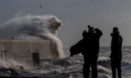 People look on as high winds from Storm Bert cause waves to crash over the harbour arm in Folkestone, Kent