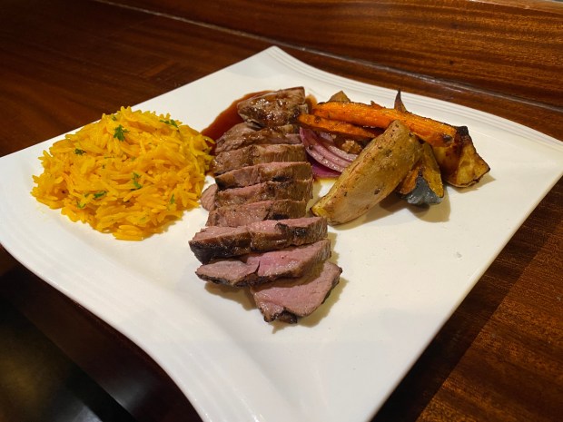 Prepared for a customer on Monday, Nov. 11, 2024 in Chico, California, this charbroiled, grass-fed leg of lamb with a pomegranate reduction sauce, saffron rice and herbed root vegetables entrée is a favorite of Cheers Chico owner David Halimi. (Kyra Gottesman/Mercury-Register)