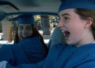 beanie feldstein and kaitlyn dever in cap and gown in a car in the movie booksmart