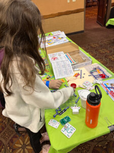 girl doing project at table with bright green tablecloth