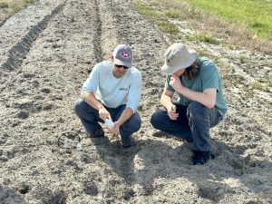 Graduate student instructs technician on how to use a soil moisture sensor 