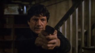 Fred Ward pointing a pistol in Remo Williams: The Adventure Begins