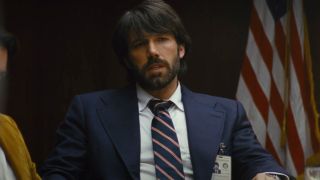 Ben Affleck in Argo sitting at a table talking.